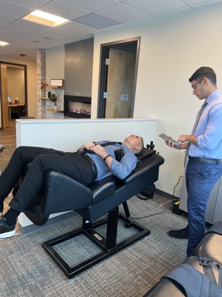 Patient receiving spinal decompression therapy while clinician monitors treatment settings.