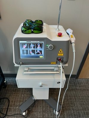 Medical laser therapy machine on wheeled stand with protective goggles on top.